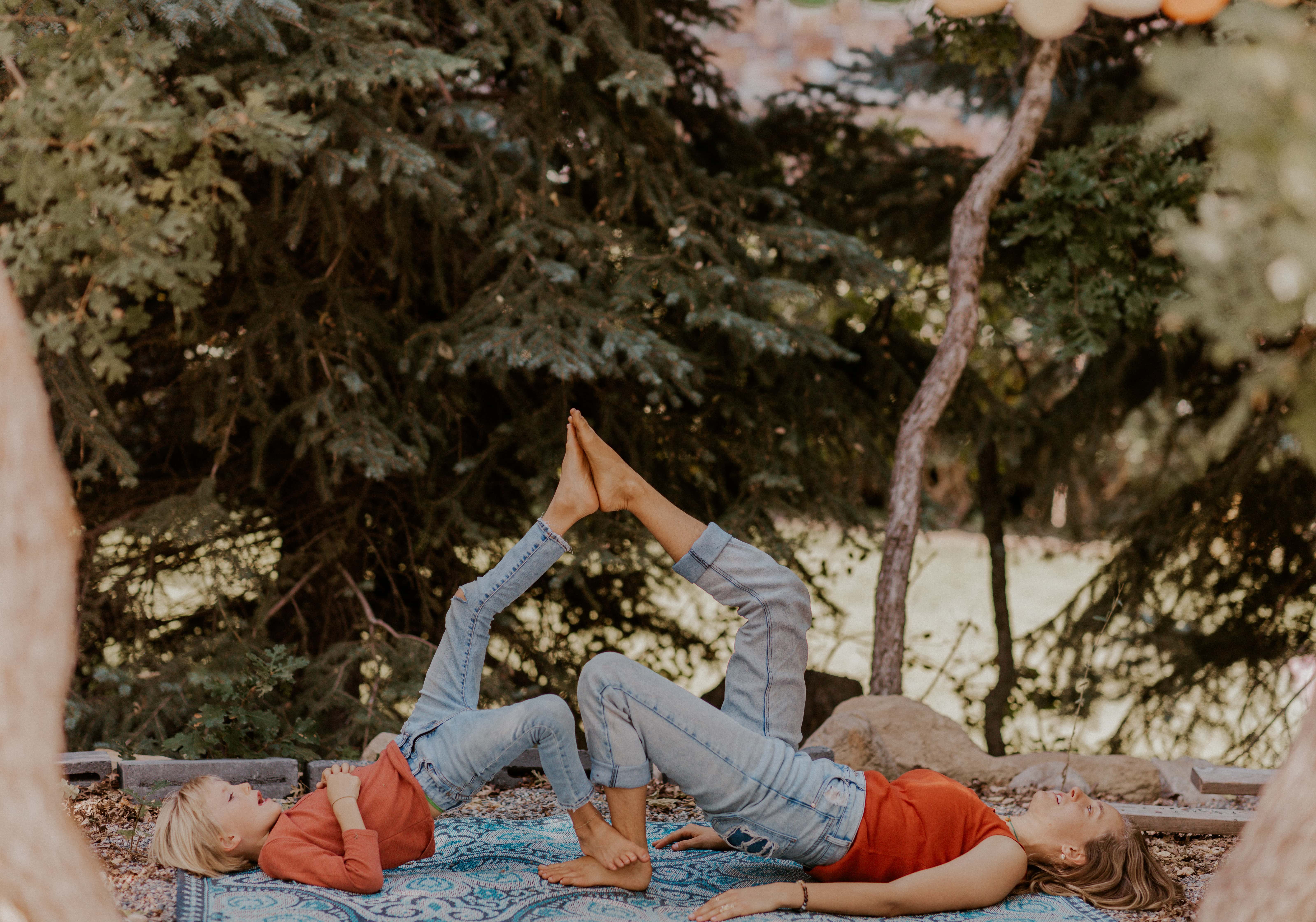 a mother and son in a single leg bridge pose with their elevated feet touching. 