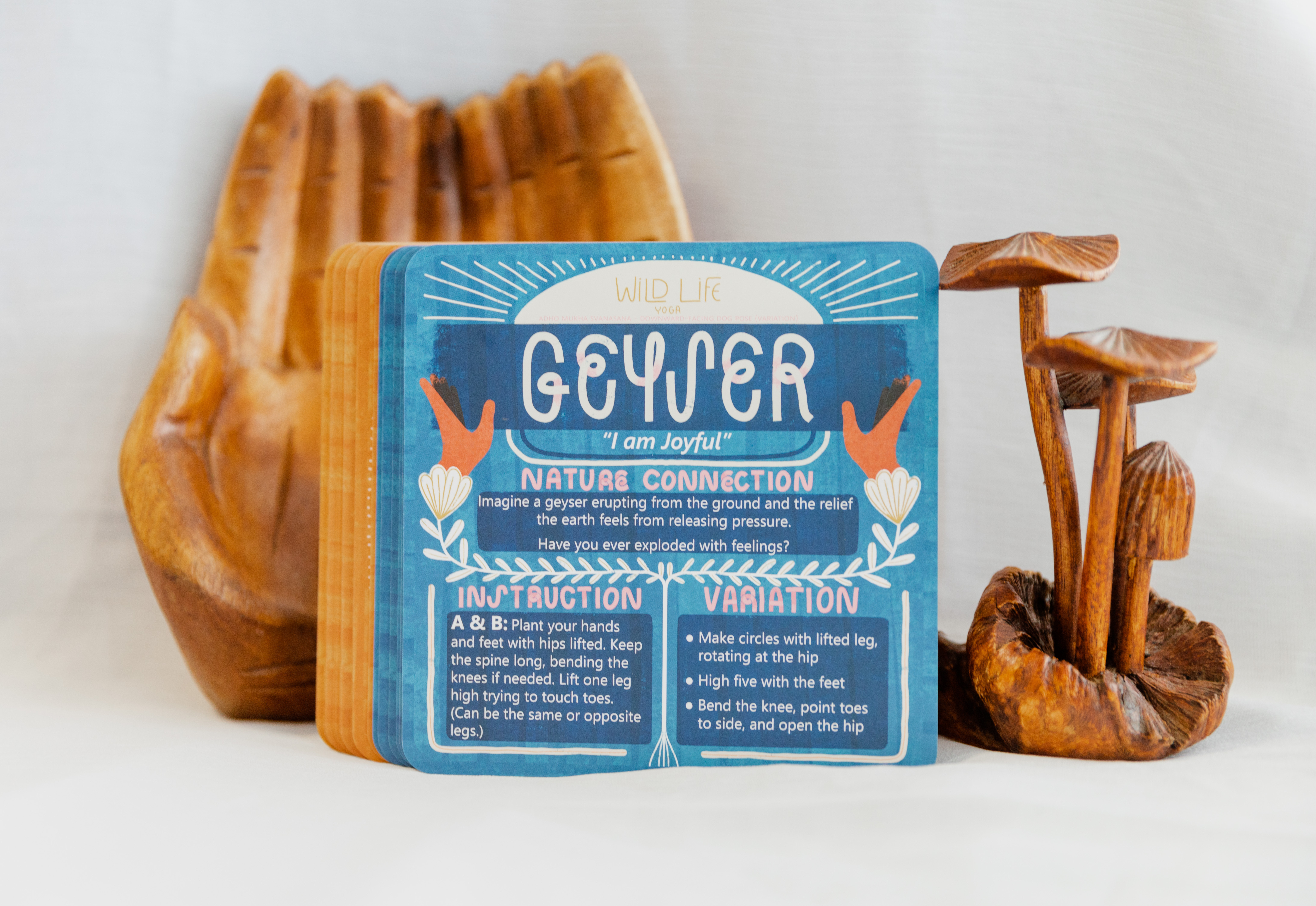 the back of the cards with wooden props behind. this shows the name of the card, an affirmation, a nature connection prompt, instructions and variations for the pose. 