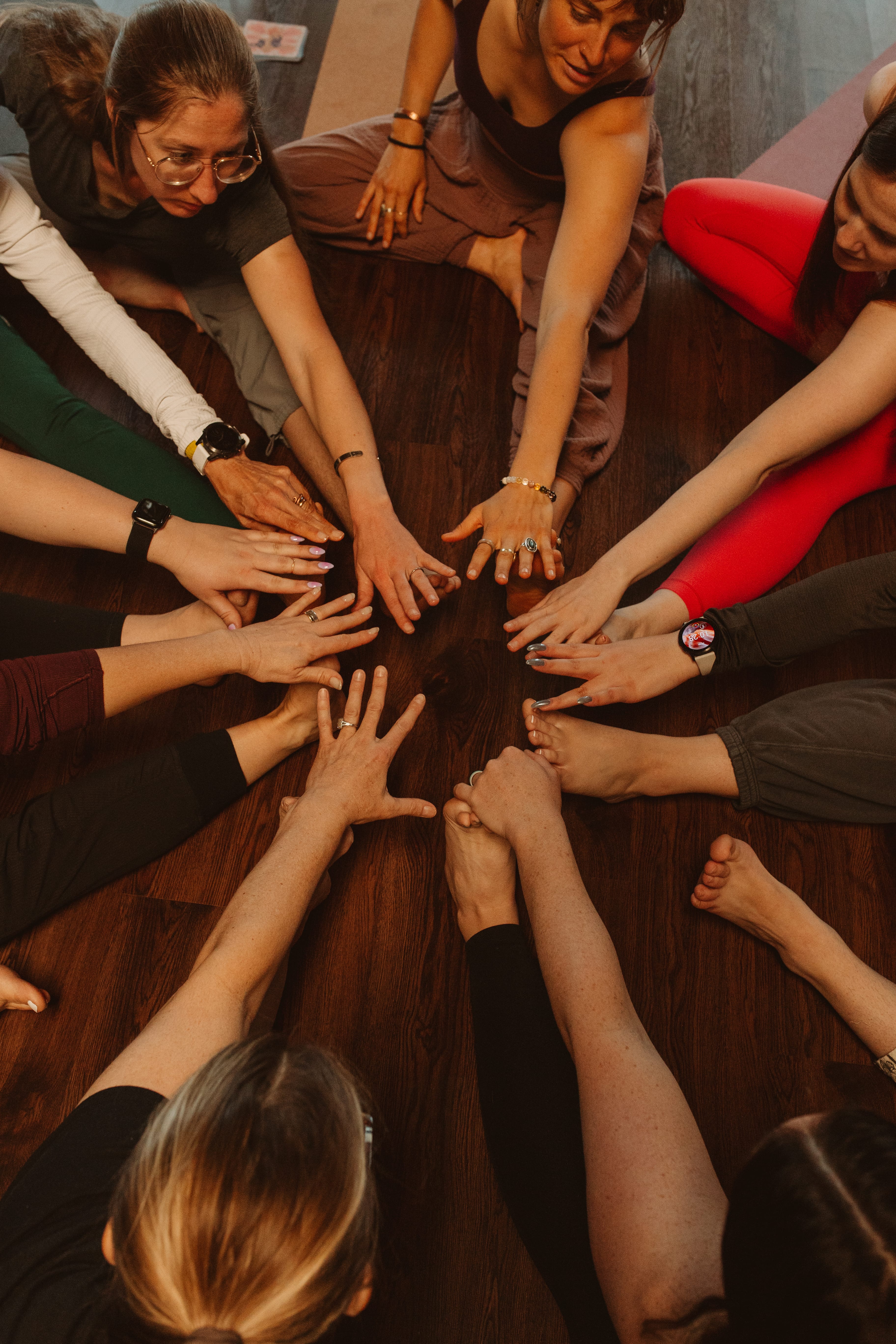 Hands coming together in the center of a circle in a single leg seated stretch group yoga pose